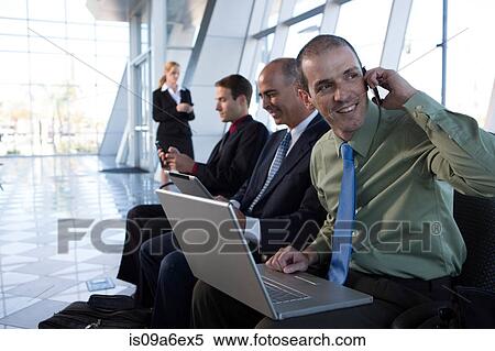 Stock Photography - Businessman on cell phone using laptop. Fotosearch