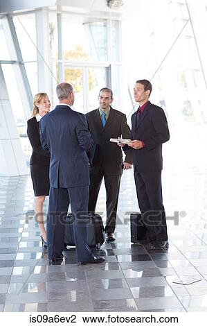 Stock Image - Businesspeople meeting in airport. Fotosearch