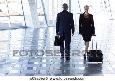 Stock Photography - Businesspeople walking through airport with suitcases. Fotosearch