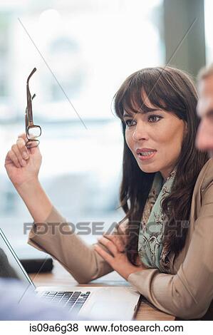 Businesswoman holding glasses using laptop View Large Photo Image Stock Photo - Businesswoman holding glasses using laptop. Fotosearch