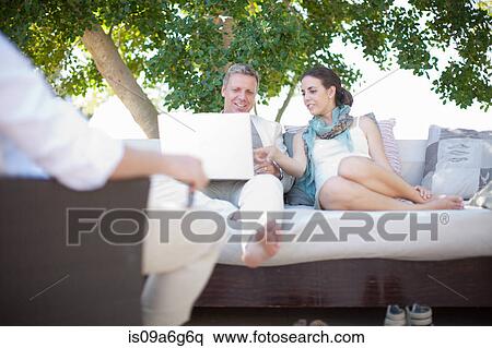 Stock Photography - Casual business people on patio using laptop. Fotosearch