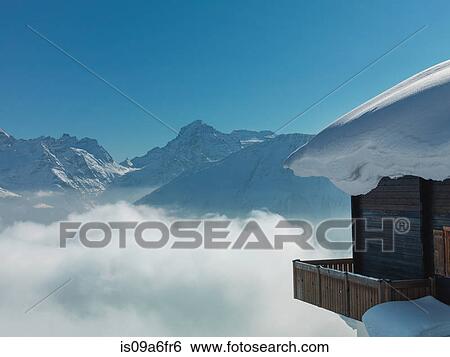 Stock Photograph - Chalet covered in snow in mountains. Fotosearch