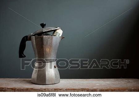 Stock Image - Coffee pot with dollar notes inside. Fotosearch