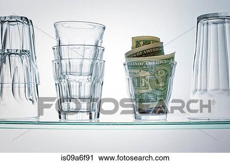 Stock Image - Dollar bills in glass on shelf. Fotosearch