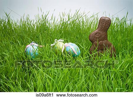 Stock Image - Easter eggs and chocolate bunny hiding in grass. Fotosearch