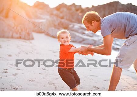 Stock Photo - Father playing with son on beach. Fotosearch