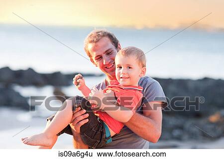 Stock Photograph - Father playing with son on beach. Fotosearch