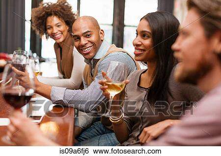 Stock Photograph - Four friends having fun at wine bar. Fotosearch