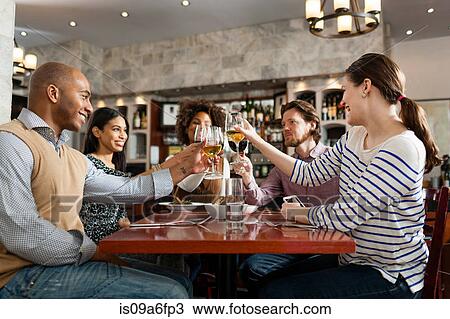 Stock Image - Friends at restaurant toasting. Fotosearch