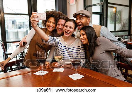 Stock Image - Friends taking photos using smart phone. Fotosearch