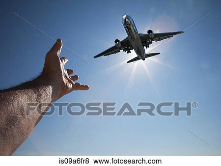 Stock Photo - Hand reaching for aeroplane in sky. Fotosearch