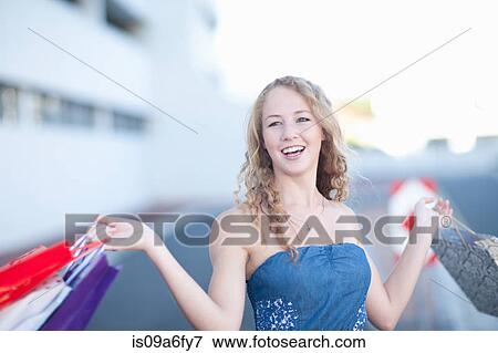 Stock Photo - Happy young women carrying shopping bags. Fotosearch