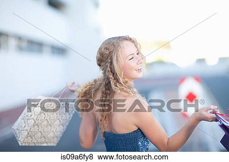 Stock Photo - Happy young women carrying shopping bags. Fotosearch