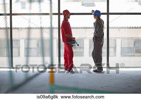 Stock Image - Laborers talking in front of window. Fotosearch