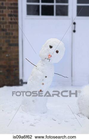 Stock Image - Leaning snowman in front of garage. Fotosearch