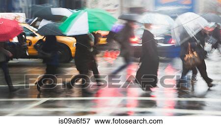Stock Photo - Line of people crossing city street in rain. Fotosearch