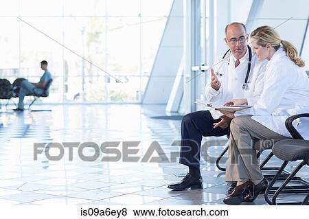 Stock Photo - Male and female doctors sitting on chairs. Fotosearch