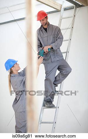 Male and female laborer with electric drill on construction site View Large Photo Image Stock Image - Male and female laborer with electric drill on construction site. Fotosearch