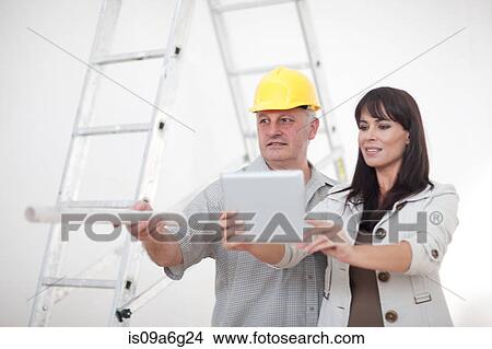 Male and female pointing and looking at computer tablet on construction site View Large Photo Image Picture - Male and female pointing and looking at computer tablet on construction site. Fotosearch