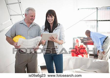 Male and female talking and smiling looking at blueprint and computer tablet on construction site View Large Photo Image Stock Image - Male and female talking and smiling looking at blueprint and computer tablet on construction site. Fotosearch