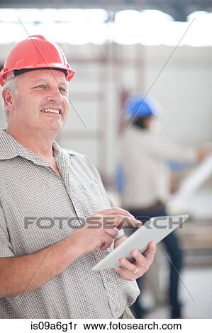Male construction worker holding a digital tablet View Large Photo Image Stock Photography - Male construction worker holding a digital tablet. Fotosearch