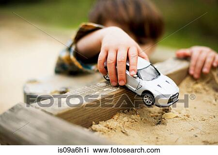 Male toddler holding toy car above sandpit View Large Photo Image Stock Image - Male toddler holding toy car above sandpit. Fotosearch
