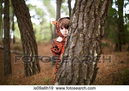 Stock Photo - Male toddler wearing tiger suit hiding behind tree. Fotosearch