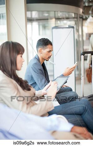 Man and woman waiting and reading digital tablets View Large Photo Image Stock Photograph - Man and woman waiting and reading digital tablets. Fotosearch