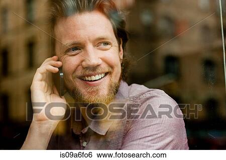 Man looking out of window talking on cell phone View Large Photo Image Stock Photograph - Man looking out of window talking on cell phone. Fotosearch