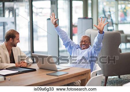 Stock Image - Mature businessman with arms up celebrating. Fotosearch