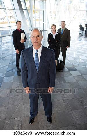 Stock Image - Mature businessman with colleagues in background. Fotosearch