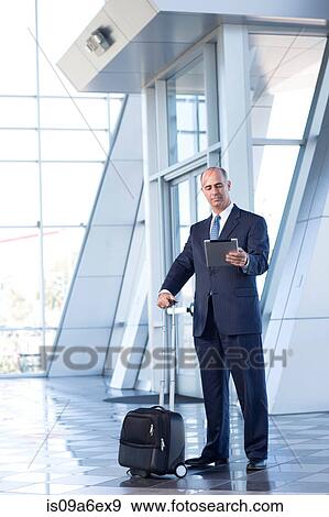 Stock Photo - Mature businessman with digital tablet and suitcase. Fotosearch