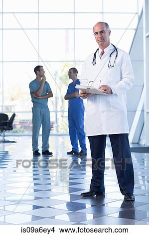Picture - Mature doctor holding medical records. Fotosearch