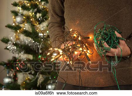 Stock Image - Mature male holding christmas tree lights. Fotosearch