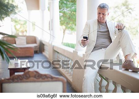 Stock Image - Mature man texting on smartphone. Fotosearch