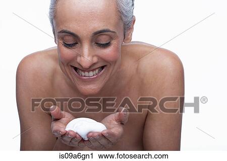 Stock Image - Mature woman cleansing face. Fotosearch