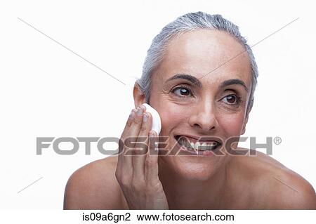Stock Image - Mature woman cleansing face. Fotosearch