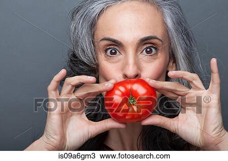 Mature woman covering mouth with red tomato View Large Photo Image Stock Image - Mature woman covering mouth with red tomato. Fotosearch