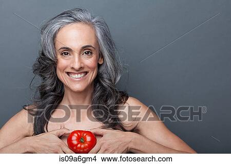Picture - Mature woman holding red tomato. Fotosearch