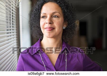 Stock Photo - Mature woman looking out of window. Fotosearch