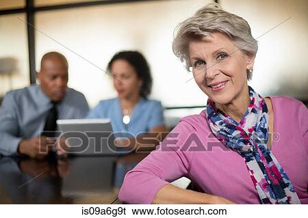 Stock Photograph - Mature woman with business colleagues in background. Fotosearch