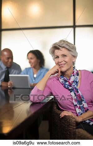 Mature woman with business colleagues in background View Large Photo Image Stock Photograph - Mature woman with business colleagues in background. Fotosearch