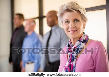 Stock Photo - Mature woman with colleagues in background. Fotosearch