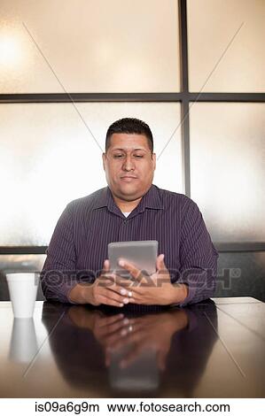 Picture - Mid adult man using digital tablet. Fotosearch