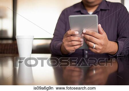 Picture - Mid adult man using digital tablet. Fotosearch