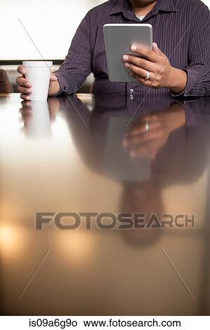Picture - Mid adult man using digital tablet. Fotosearch