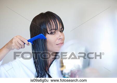 Stock Photograph - Mid adult woman combing wet hair. Fotosearch