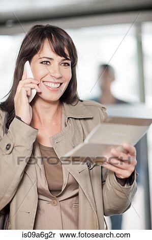Mid adult woman smiling on mobile phone View Large Photo Image Stock Photography - Mid adult woman smiling on mobile phone. Fotosearch