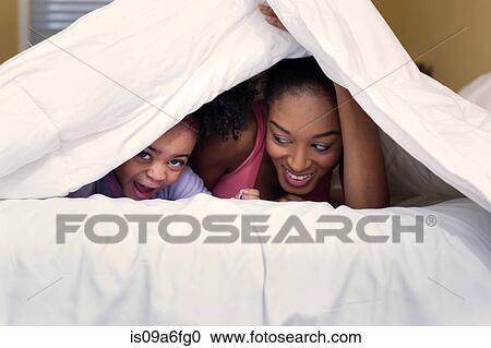 Mother and daughter playing on bed hiding under duvet View Large Photo Image Stock Image - Mother and daughter playing on bed hiding under duvet. Fotosearch