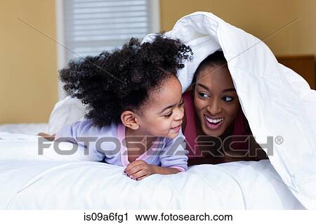 Mother and daughter playing on bed hiding under duvet View Large Photo Image Stock Image - Mother and daughter playing on bed hiding under duvet. Fotosearch